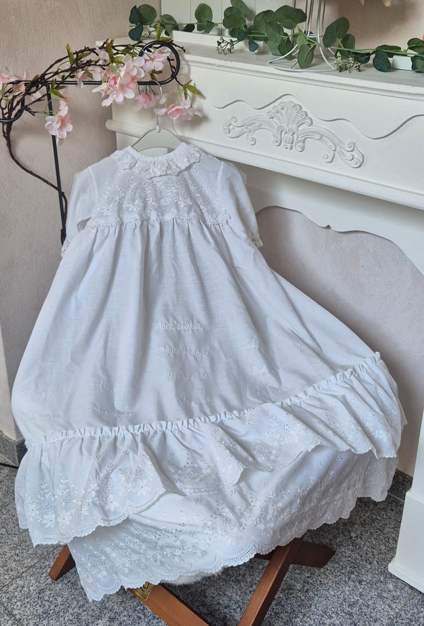 Traditionelles handgefertigtes Taufkleid mit eingestickten Namen und Taufdaten mehrerer Generationen als Familienerbstück.